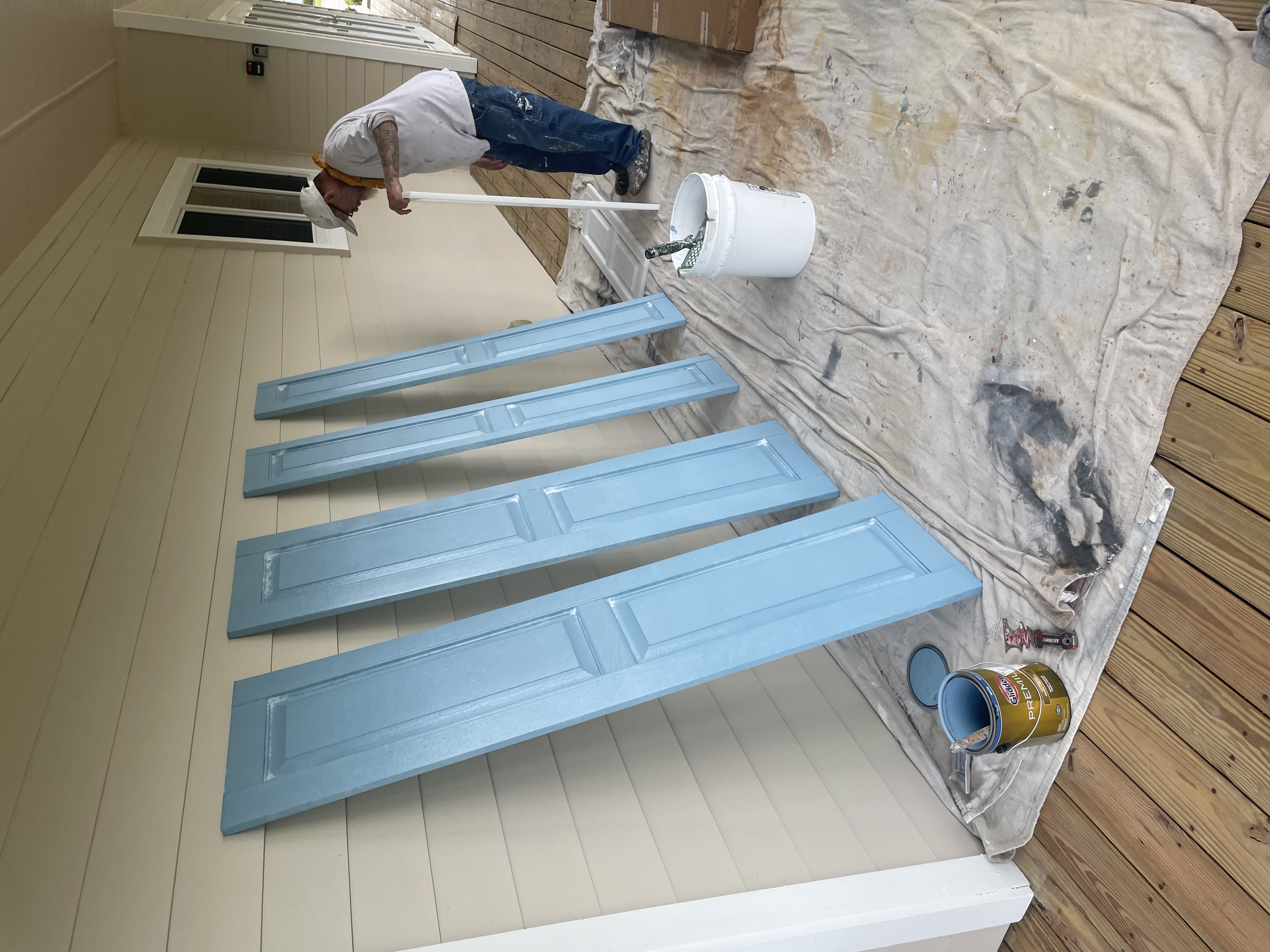Painter working on blue shutters